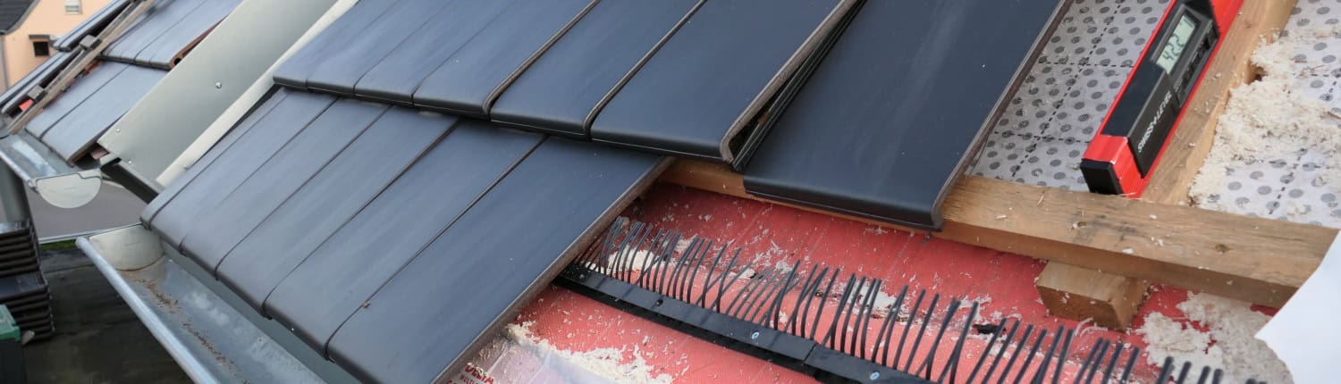 Prüfung der Verlegung der Unterspannbahn Baustellenansicht eines Steildachs während der Eindeckung; sichtbar sind die DELTA Folienbahnen, die Konterlattung sowie der montierte Traufkamm zur Vogelabwehr.