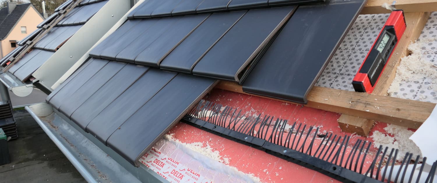 Prüfung der Verlegung der Unterspannbahn Baustellenansicht eines Steildachs während der Eindeckung; sichtbar sind die DELTA Folienbahnen, die Konterlattung sowie der montierte Traufkamm zur Vogelabwehr.