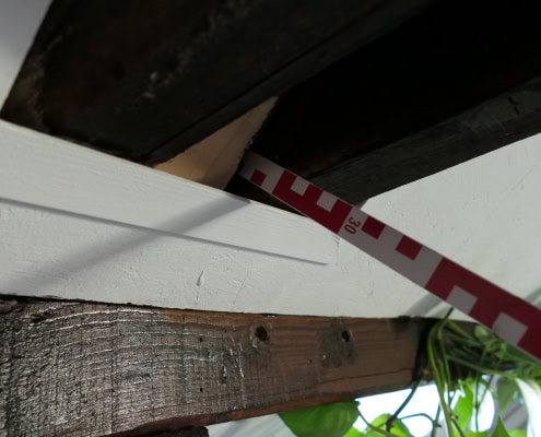 P1023418 Prüfung der Luftdichtheitsebene: Ein Meterstab wird an einer Fehlstelle der Dampfbremsbahn tief in den gedämmten Dachaufbau eingeschoben, was eine massive Leckage und das Risiko für Wasserdampfkonvektion belegt.