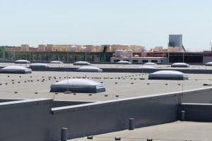 Industrielles Flachdach mit zahlreichen Lichtkuppeln Eine Außenaufnahme eines weitläufigen Flachdachs, auf dem eine Vielzahl von Lichtkuppeln zur natürlichen Belichtung der Innenräume installiert ist.